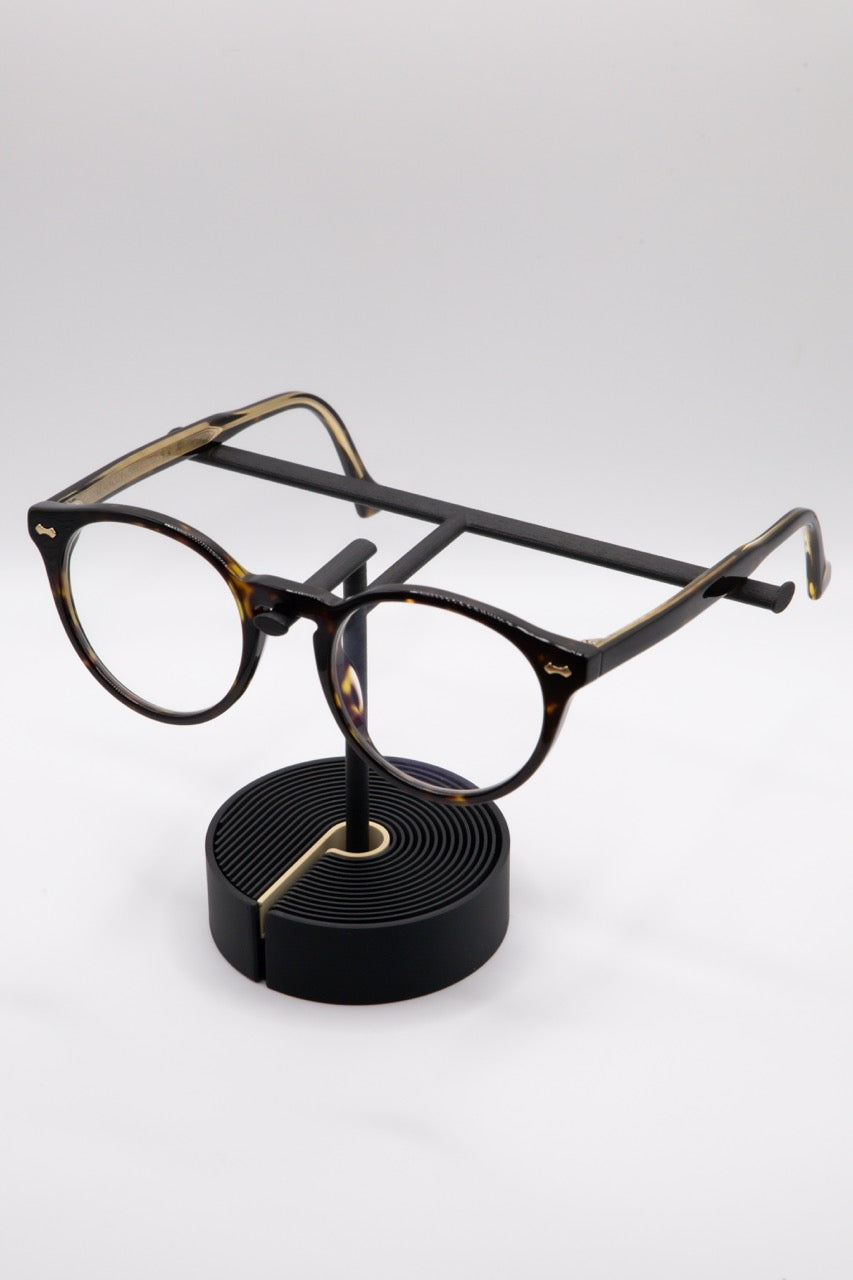 Brillenhalter PureStand in Schwarz matt mit runder schwarzer Base, beigem Einlegeteil und Brille aufgesetzt.
