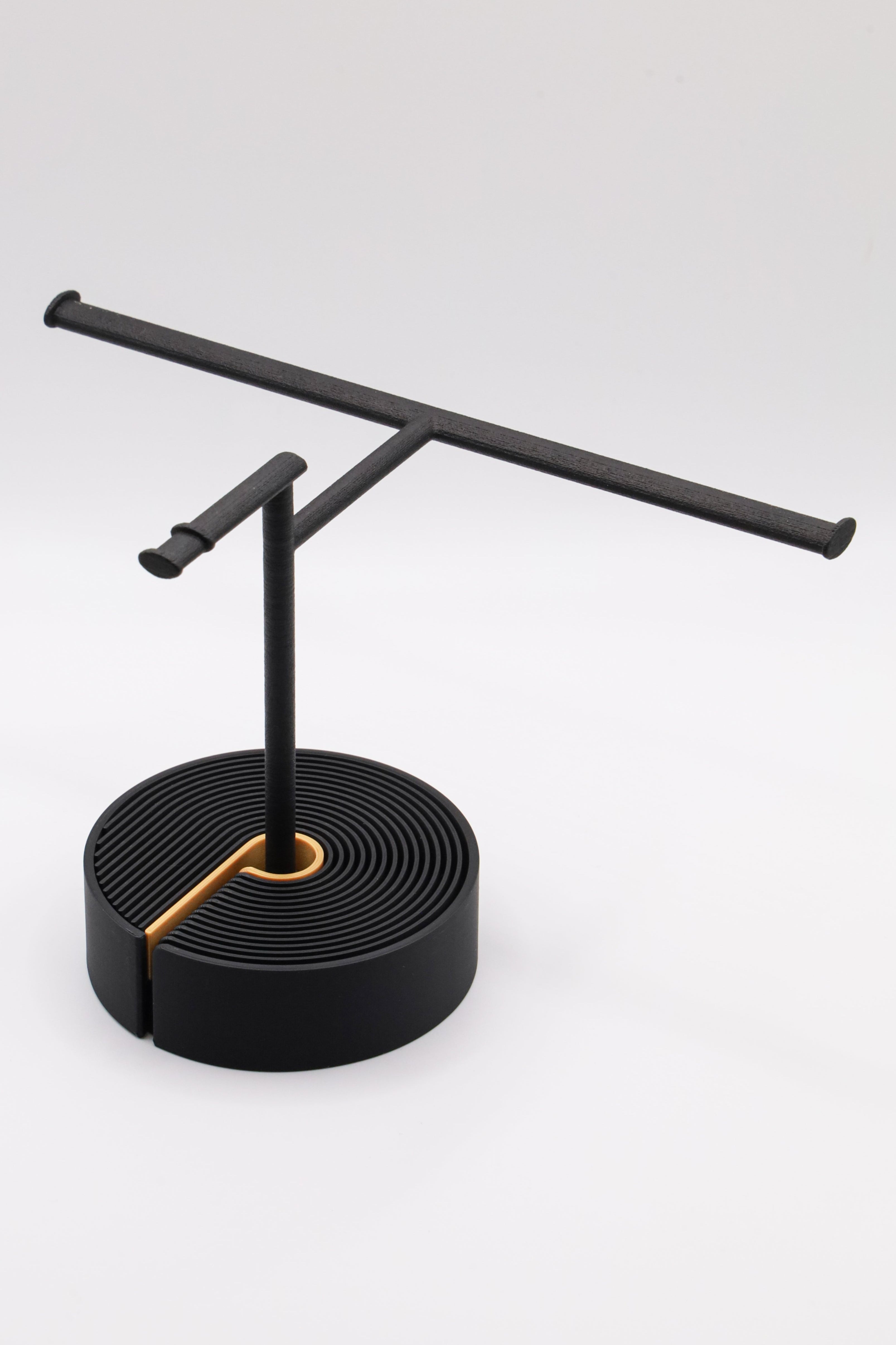 Brillenhalter PureStand in Schwarz matt mit runder schwarzer Base und goldenem Einelegeteil.