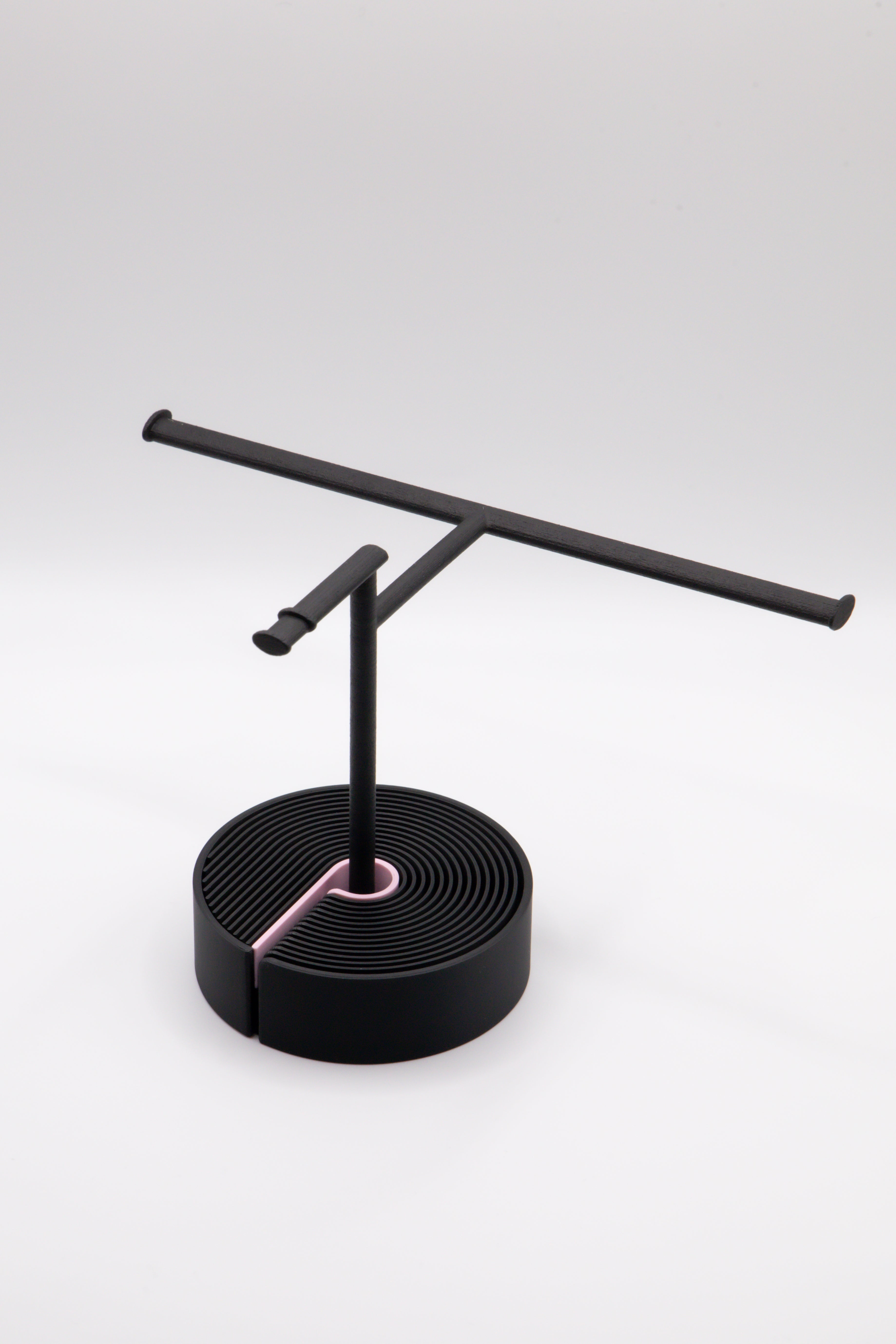 Brillenhalter PureStand in Schwarz matt mit runder schwarzer Base und pinkem Einelegeteil.