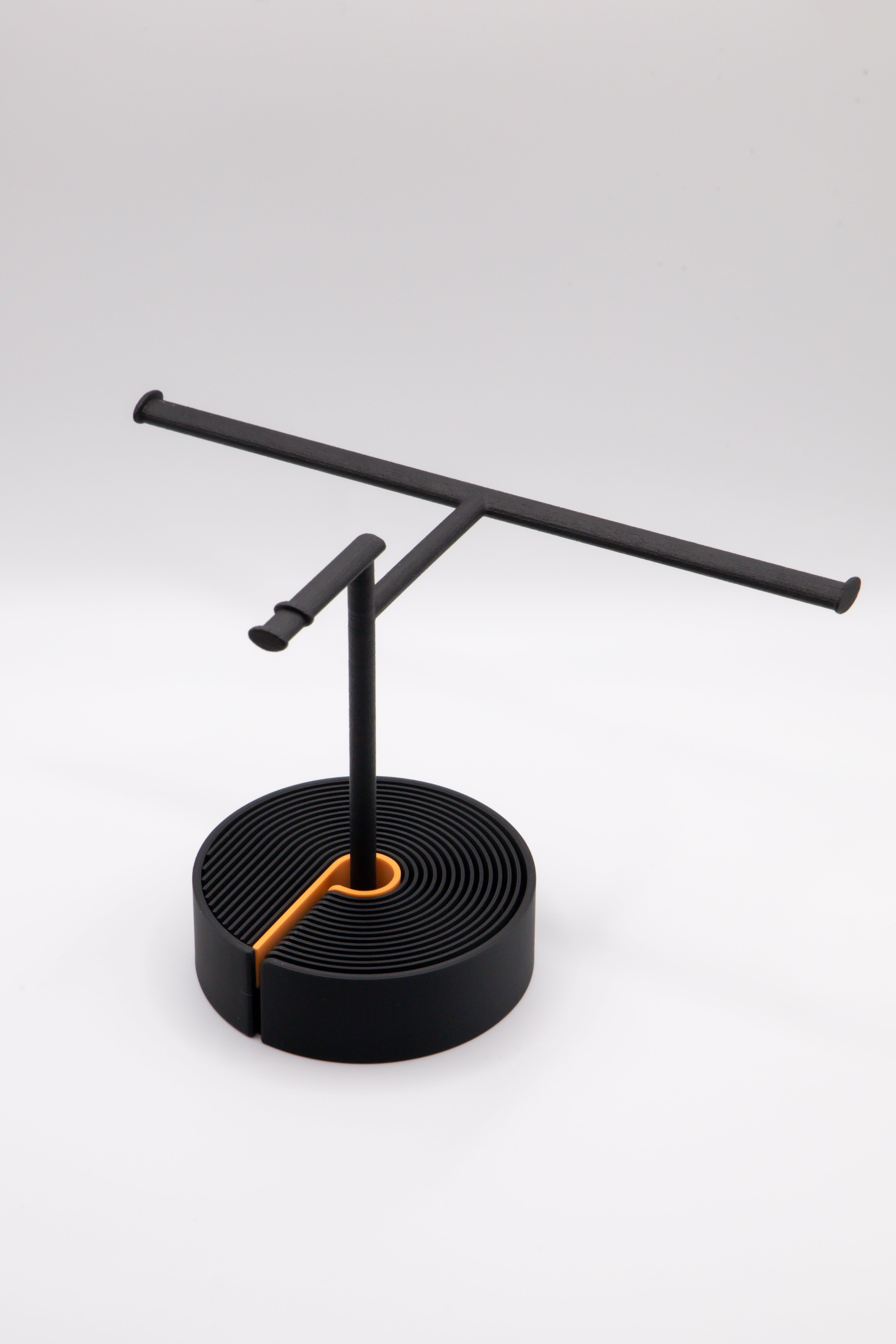 Brillenhalter PureStand in Schwarz matt mit runder schwarzer Base und orangenem Einelegeteil.