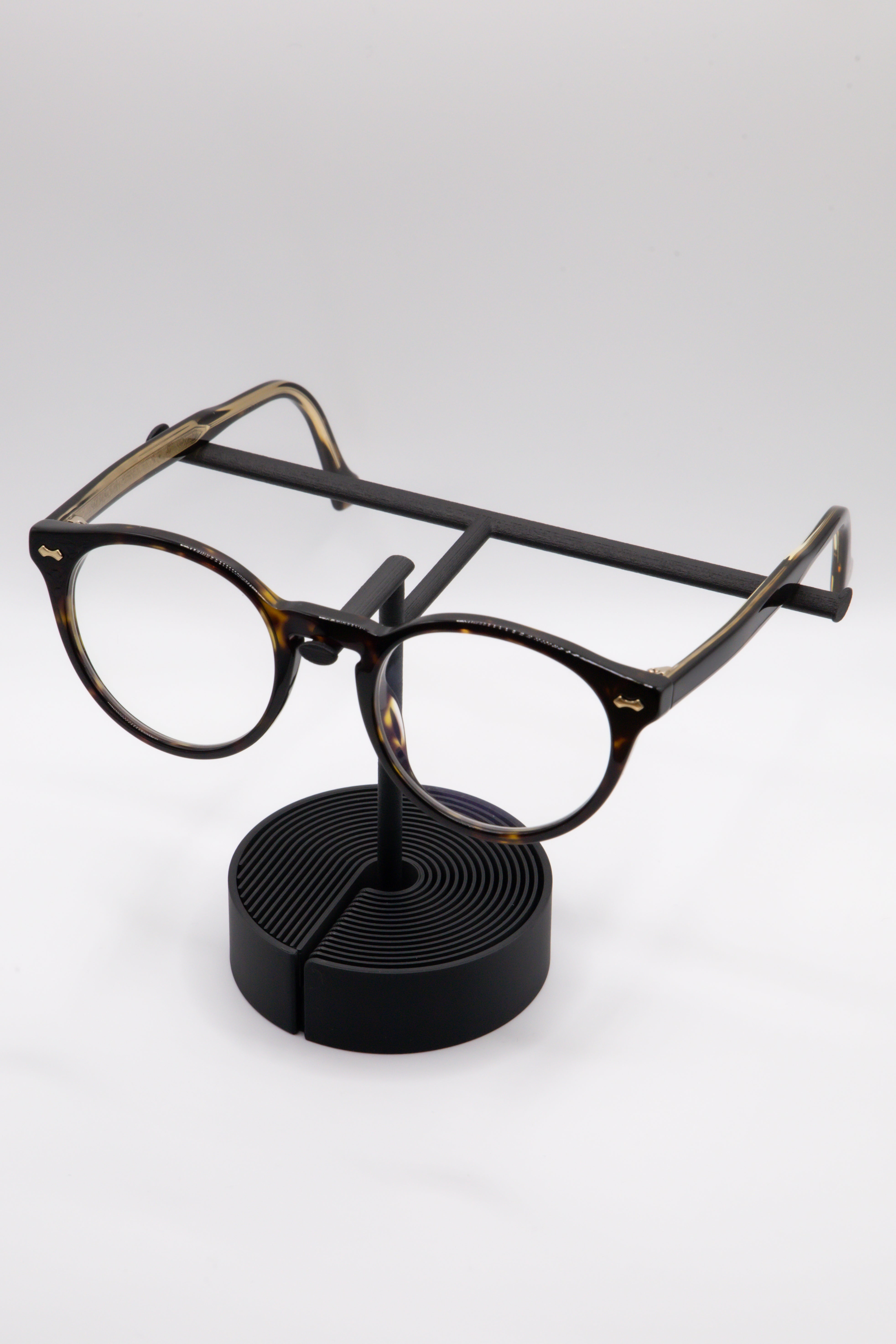 Brillenhalter PureStand in Schwarz matt mit runder schwarzer Base, schwarzem Einlegeteil und Brille aufgesetzt.